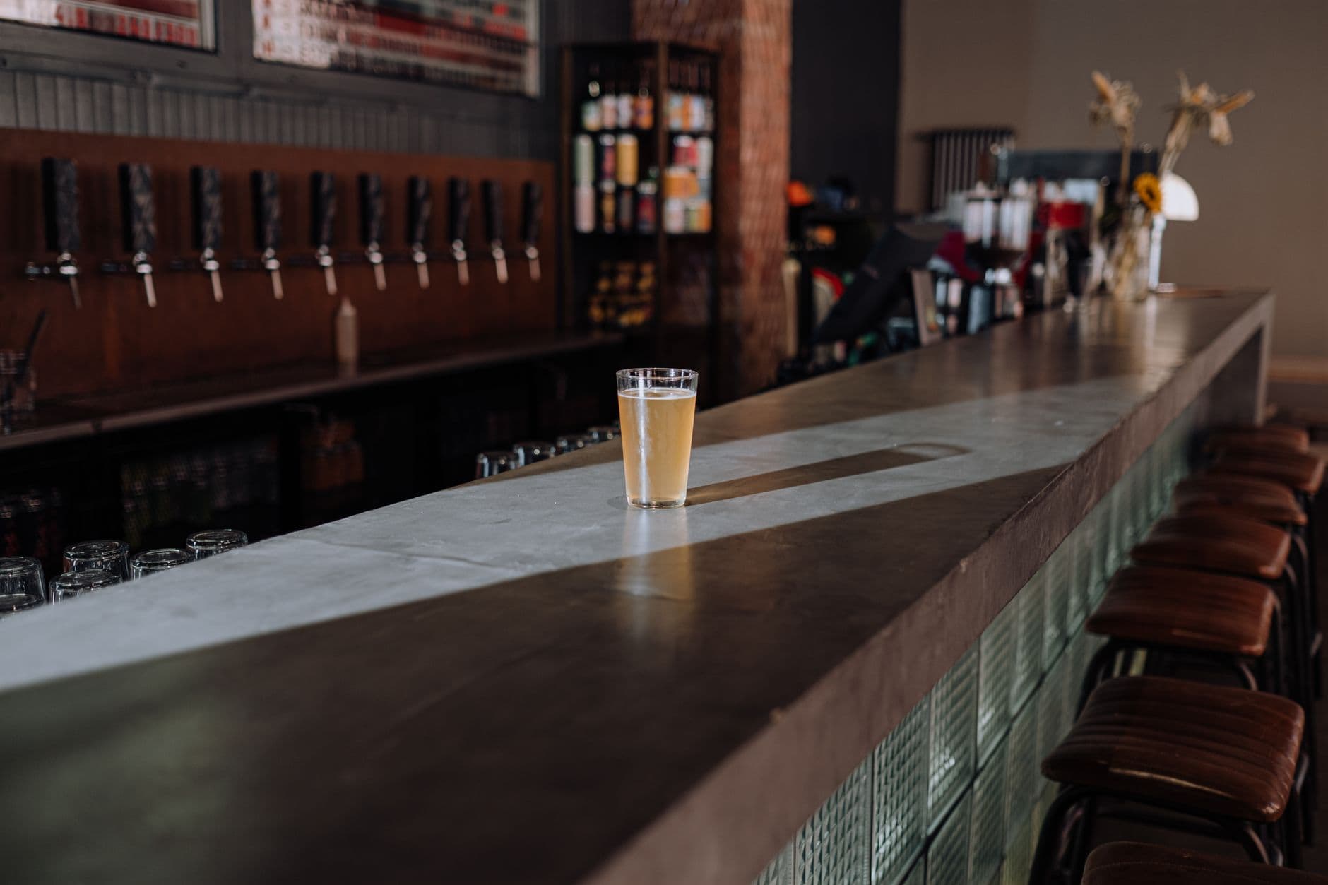 A refreshing glass of craft beer sits on a sleek bar counter, perfect for a modern pub setting. — Photo by cottonbro studio on Pexels