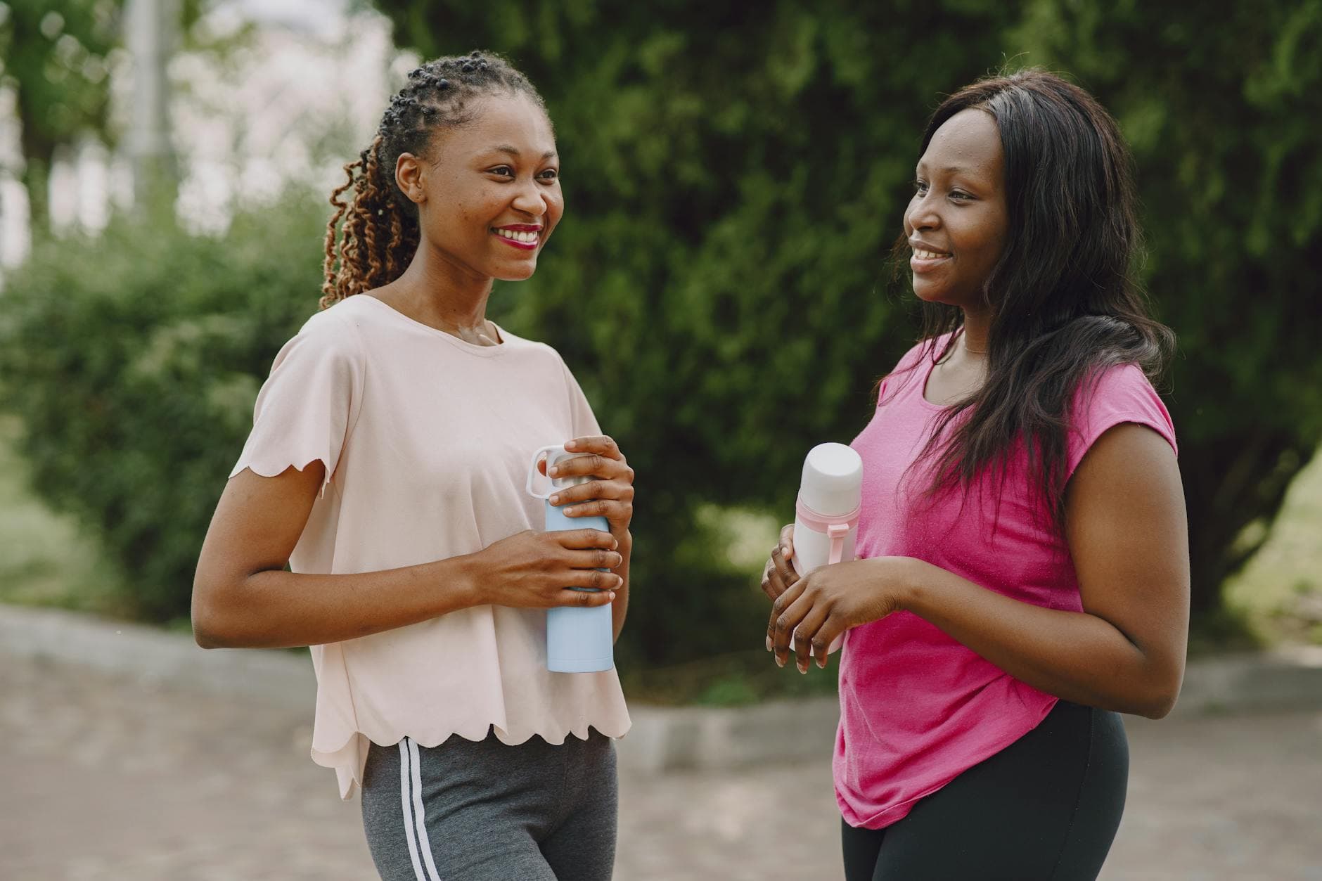 Two women chatting cheerfully outdoors holding tumblers. — Photo by Gustavo Fring on Pexels